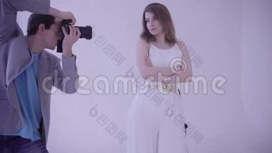 拍照。 年轻的欧洲妇女穿着白色连衣裙在摄影棚拍照。